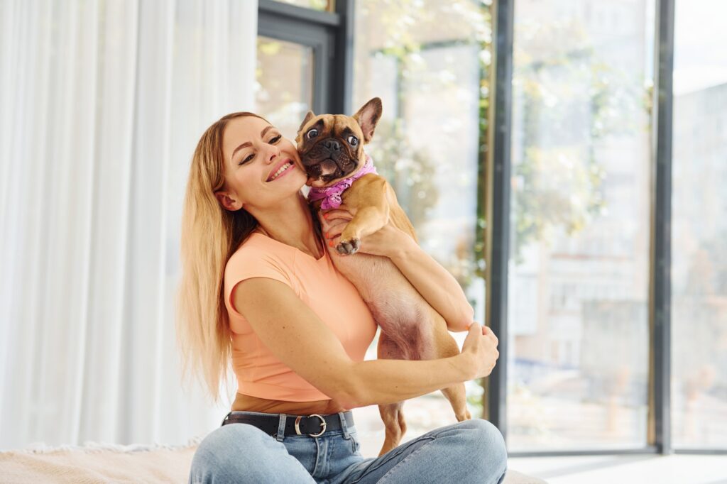 Embracing the pet. Woman with pug dog is at home at daytime
